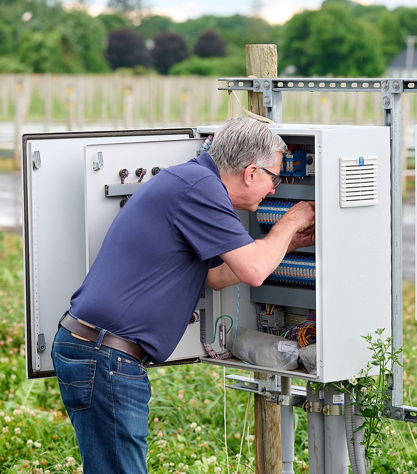 TC Controls technician working on an open greenhouse control panel